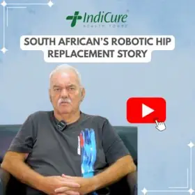 A headshot of a South African man named Andrew, wearing a black t-shirt, sharing his story about a robotic hip replacement in India through IndiCure Health Tours.